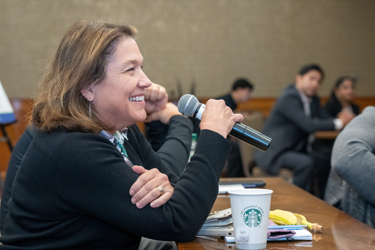 Woman speaks on microphone in conference room.