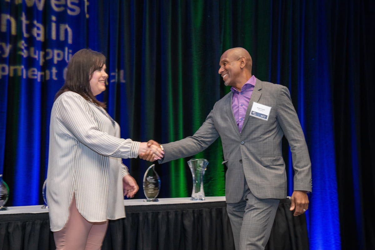 WEB-_A1_2128-Seattle-Event-Photographer-Mike-Nakamura-Photography Two people shake hands on stage.