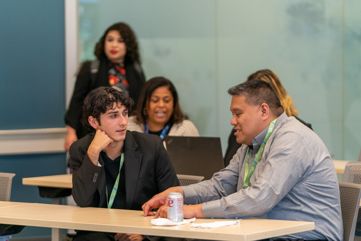 Two people converse in a classroom.