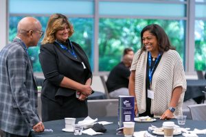 Three people network at a conference.